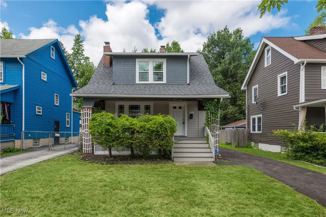 Bungalow with a shingled roof, a chimney, a porch, and asphalt driveway