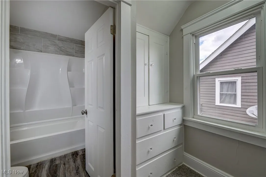Full bath featuring vaulted ceiling, shower / bathtub combination, and wood finished floors