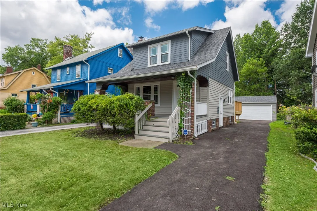 Bungalow-style house featuring covered porch, an outbuilding, roof with shingles, a front yard, and a garage