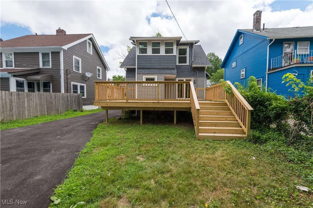 Rear view of house featuring a wooden deck, stairs, and roof with shingles