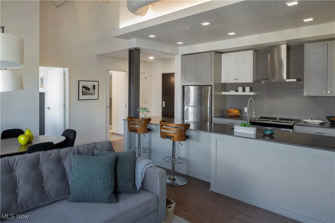 Kitchen with refrigerator, stainless steel appliances, dark wood-style flooring, and tasteful backsplash
