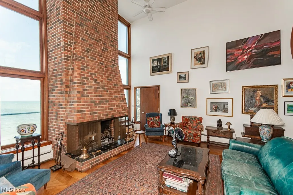 Living area featuring a towering ceiling, a ceiling fan, a fireplace, and a water view