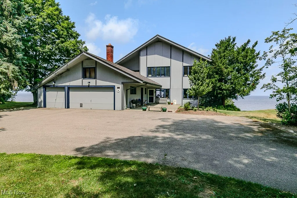 View of front of house featuring a water view, a chimney, an attached garage, and driveway