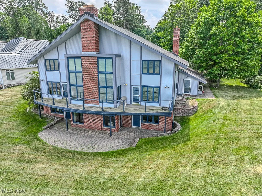 Back of property featuring a chimney, a patio, a yard, and brick siding