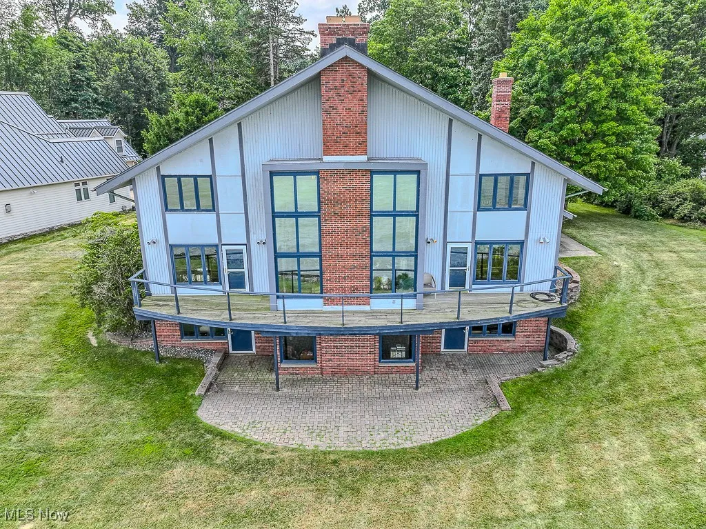 Rear view of house featuring a balcony, a patio area, a yard, and a chimney