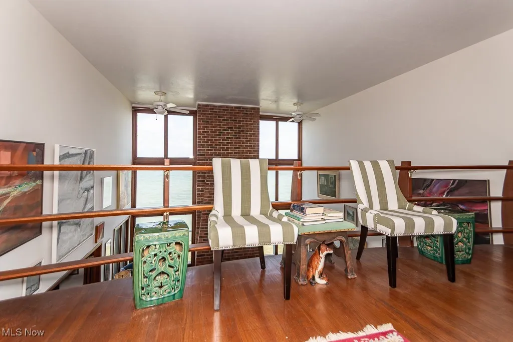 Sitting room with ceiling fan, wood finished floors, and a wall of windows