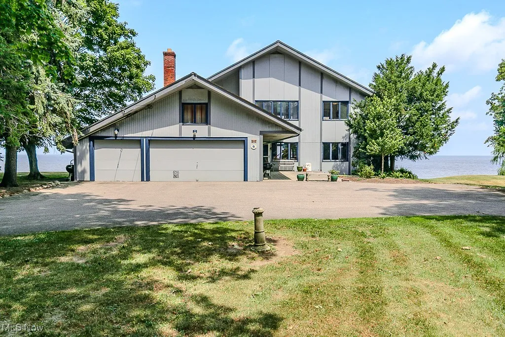 View of front of house with a water view, a front lawn, an attached garage, and a chimney