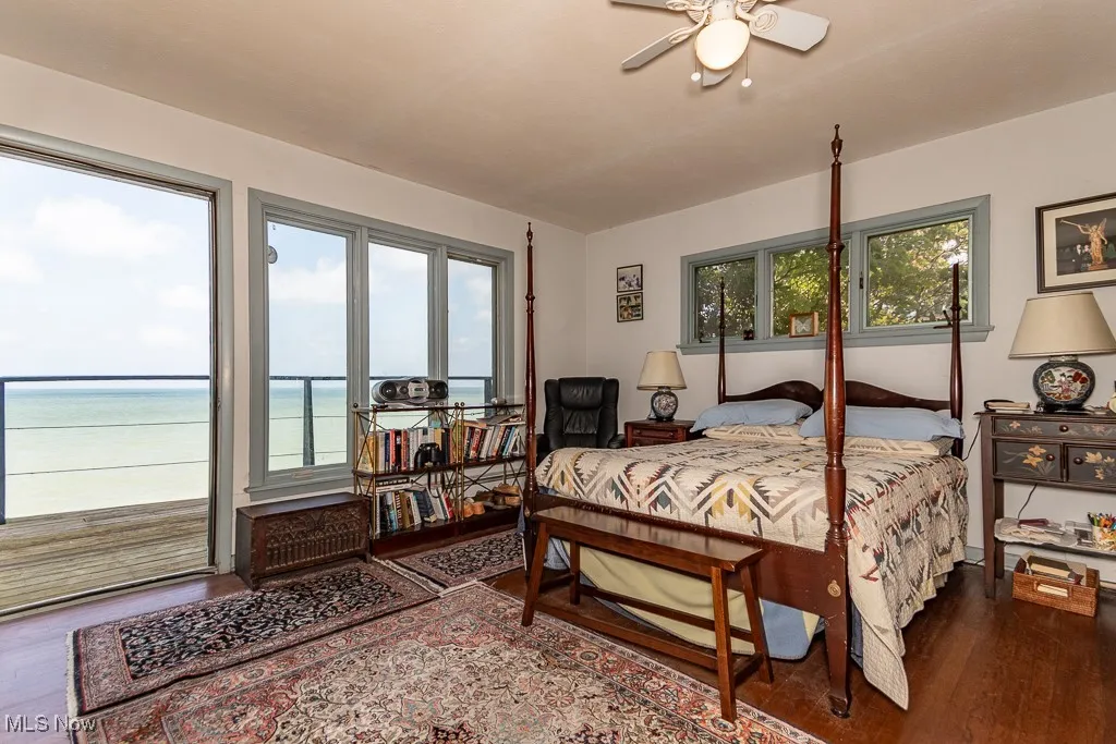 Bedroom with wood finished floors, access to exterior, and a water view