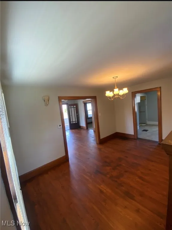 Empty room with a chandelier and wood finished floors