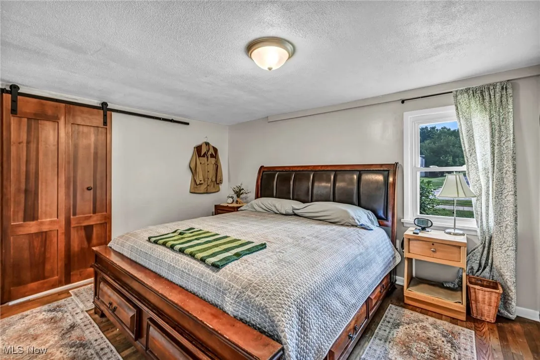 Bedroom with wood finished floors, a textured ceiling, and a barn door