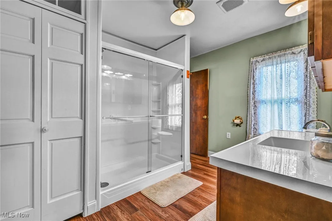 Bathroom featuring vanity, a stall shower, and wood finished floors