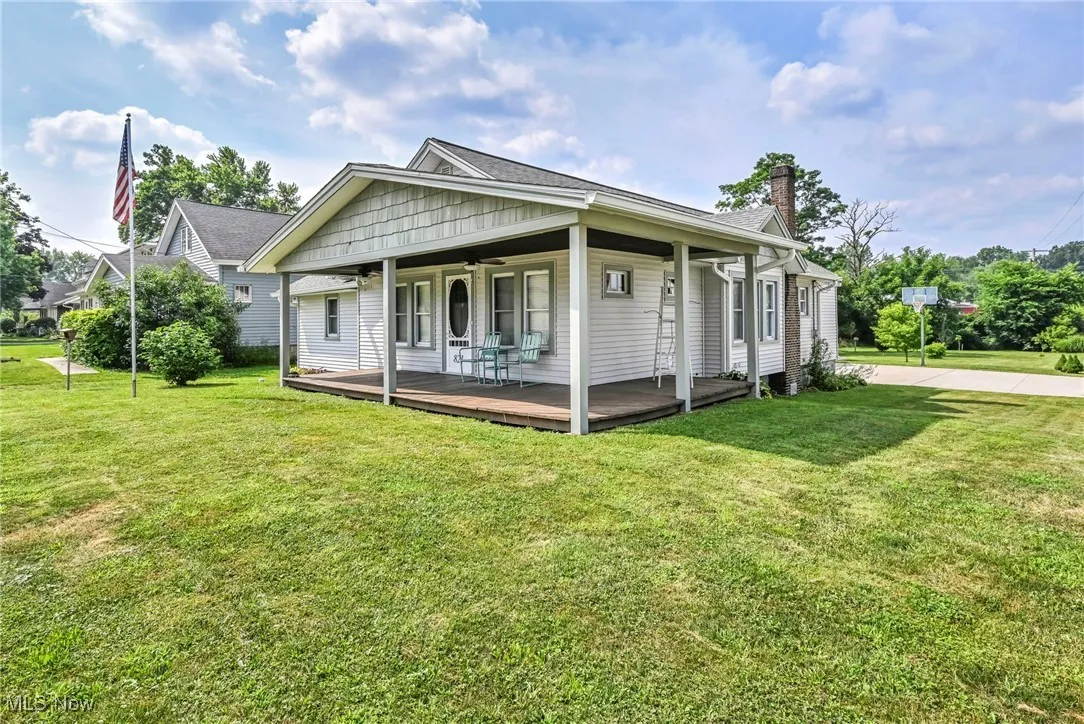 View of front of property with a front yard, ceiling fan, a chimney, and a porch