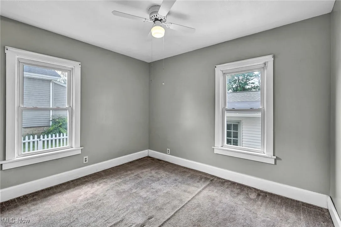 Carpeted spare room with baseboards and ceiling fan