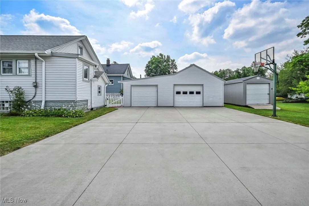 View of side of property with a detached garage, an outbuilding, and a lawn
