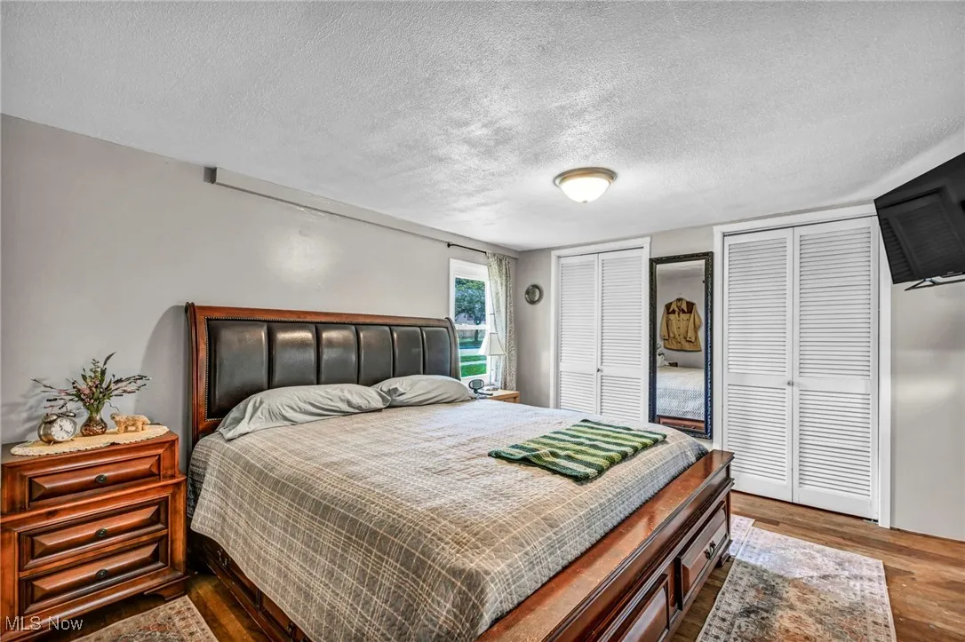 Bedroom featuring multiple closets, wood finished floors, and a textured ceiling
