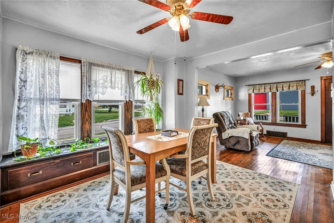 Dining space with a ceiling fan, hardwood / wood-style floors, and a textured ceiling