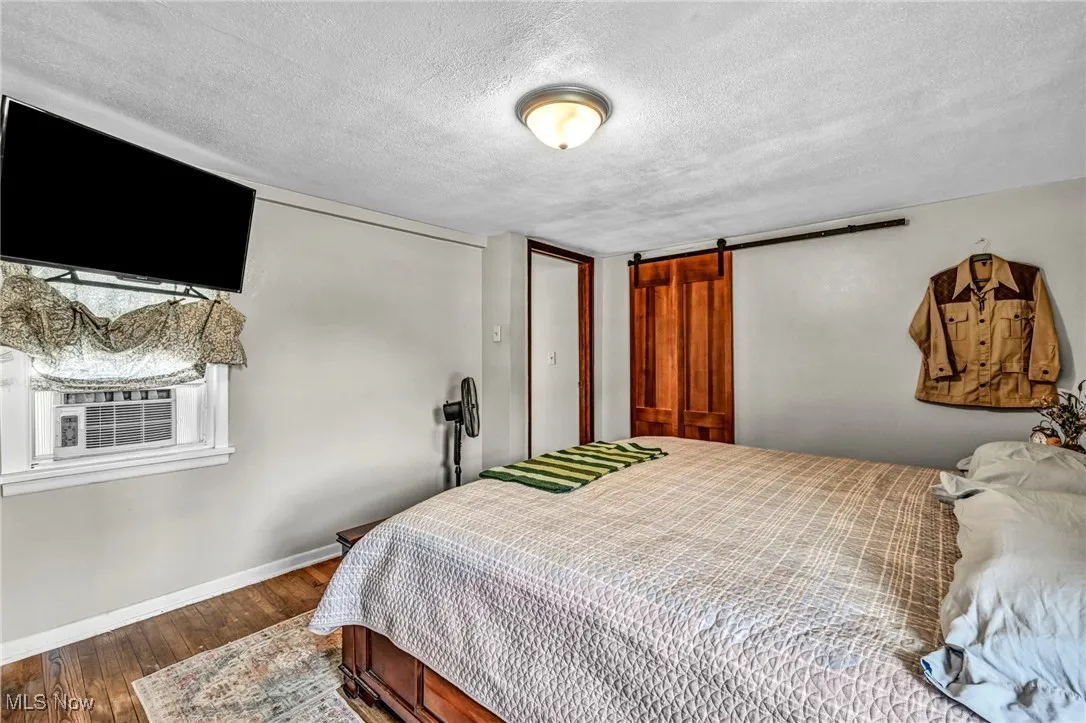 Bedroom featuring wood finished floors, a textured ceiling, and a barn door