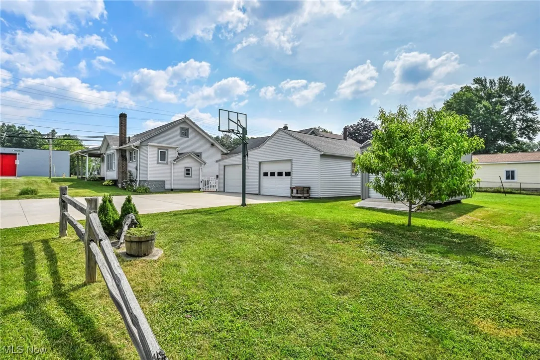 Rear view of house with concrete driveway, a garage, and an outbuilding