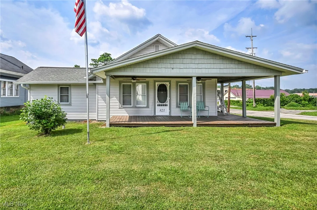 View of front of home with a porch with ceiling fan, a front lawn, a shingled roof, and covered porch