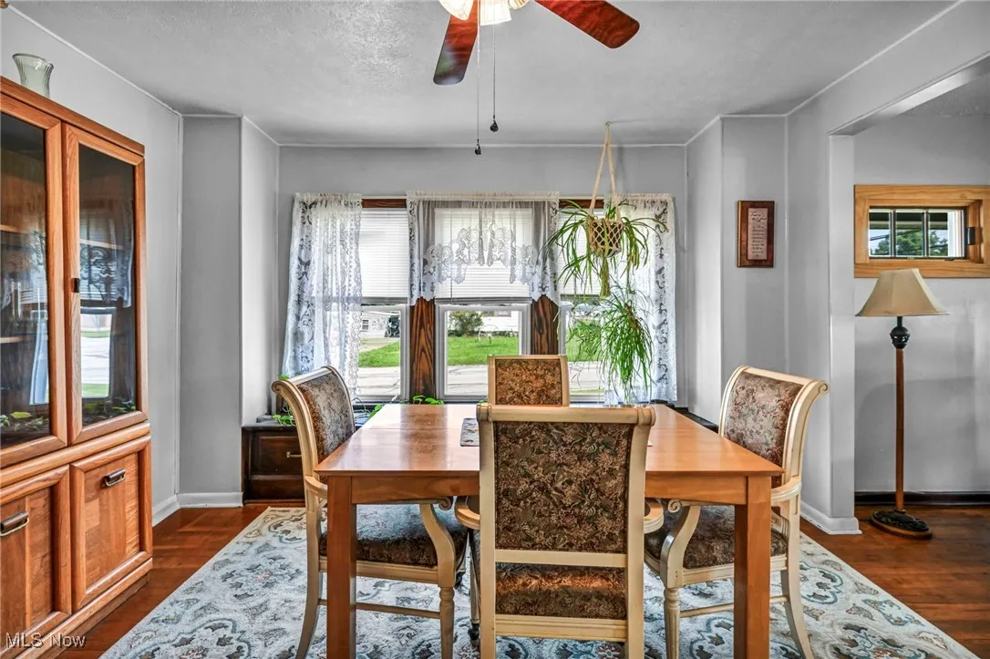 Dining area featuring ceiling fan, dark wood-type flooring, and a textured ceiling