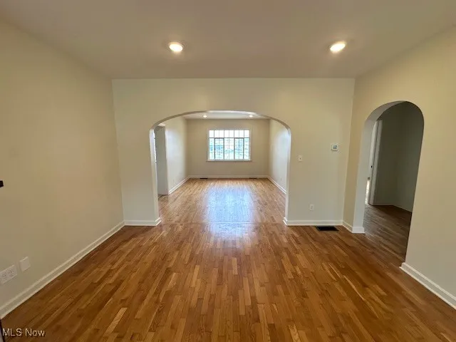 Spare room with arched walkways, wood finished floors, and recessed lighting