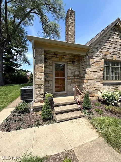 Entrance to property featuring stone siding and a chimney