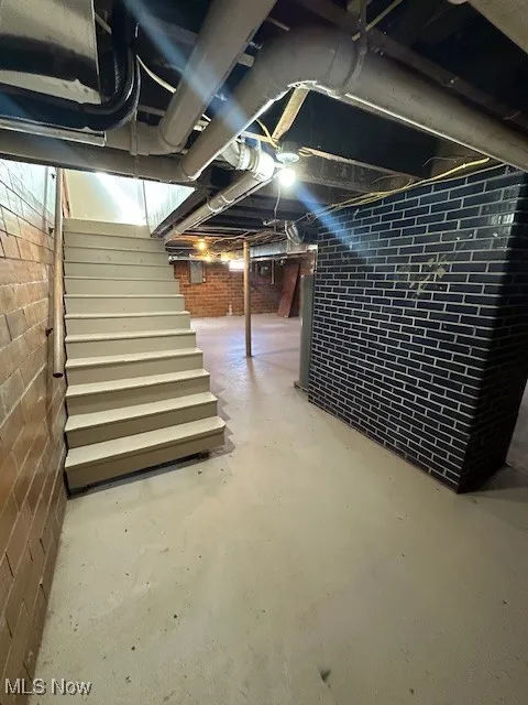 Unfinished below grade area featuring stairs and electric panel