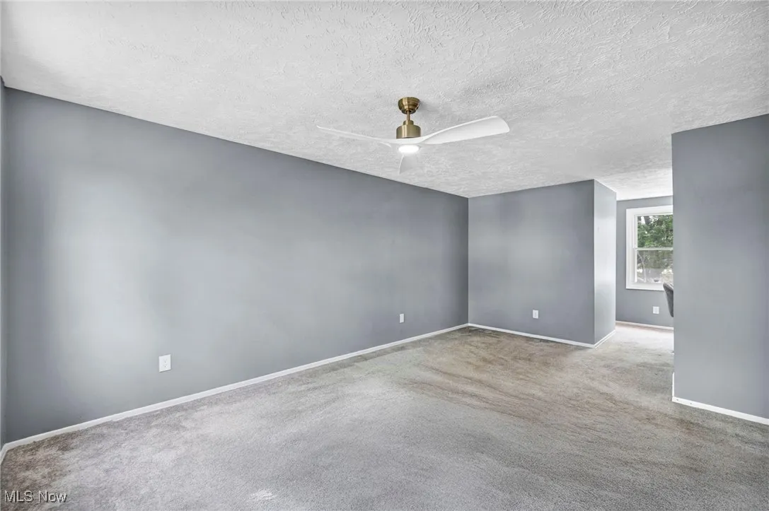 Carpeted spare room with a textured ceiling and ceiling fan
