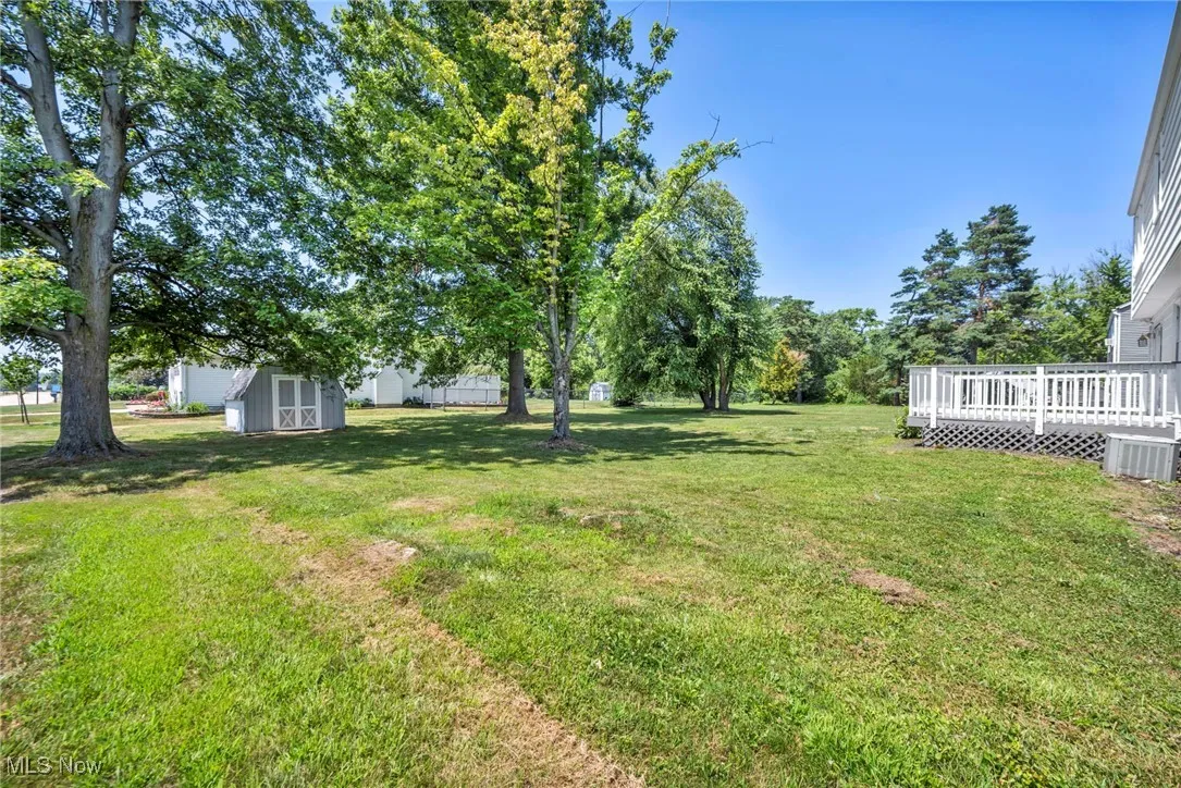 View of grassy yard featuring a storage shed and a deck