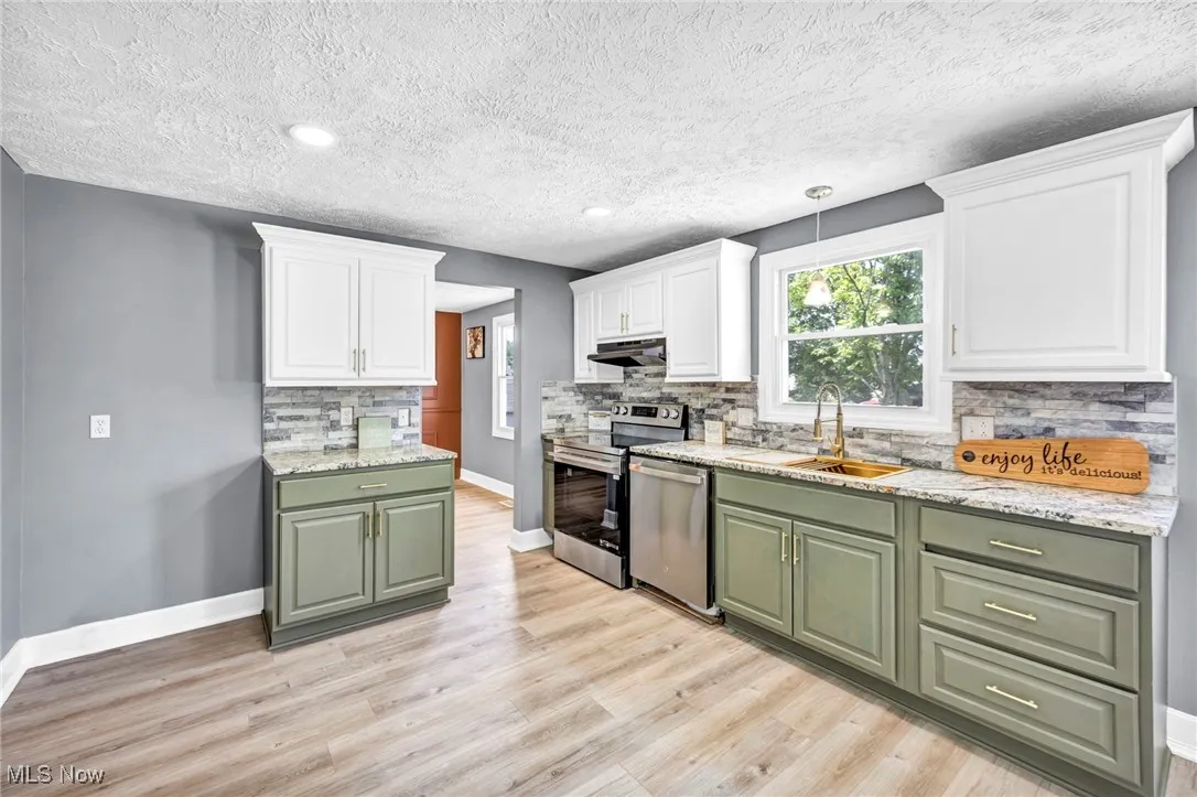 Kitchen featuring green cabinets, white cabinets, backsplash, a textured ceiling, and recessed lighting