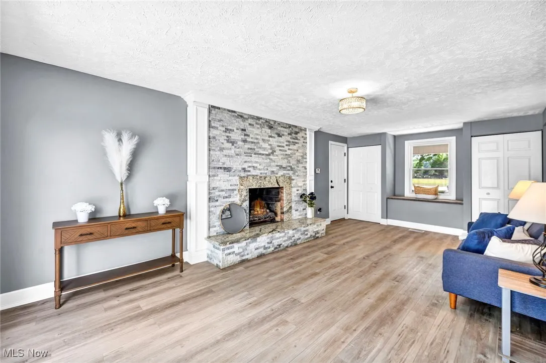 Living area featuring a textured ceiling, wood finished floors, and a fireplace