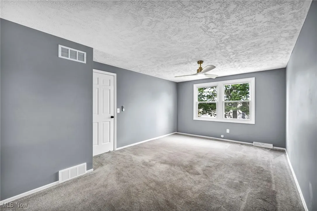 Carpeted spare room featuring a ceiling fan and a textured ceiling