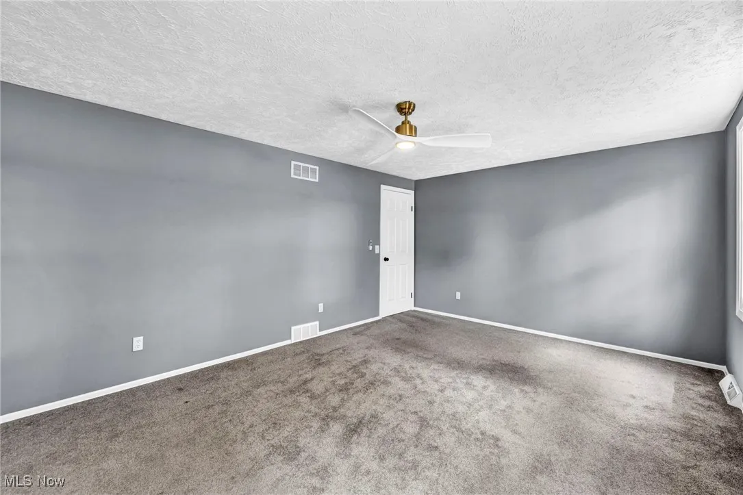 Carpeted spare room featuring ceiling fan and a textured ceiling