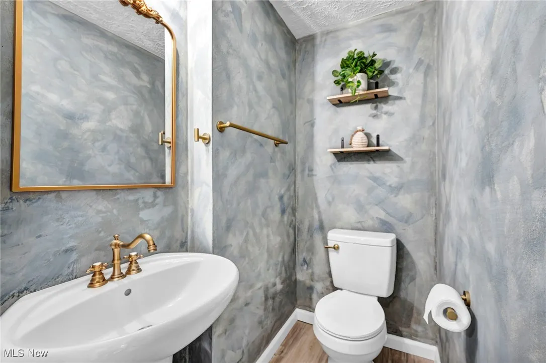 first floor - Half bathroom with wood finished floors and a textured ceiling