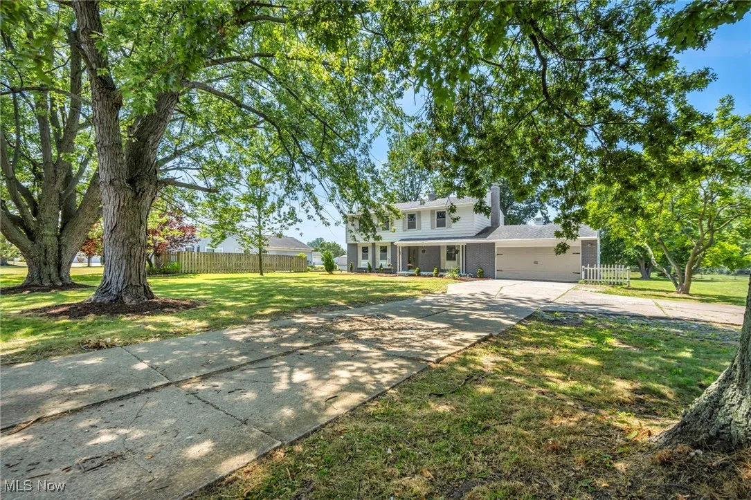 Traditional-style house with concrete driveway, a garage, covered porch, and a chimney