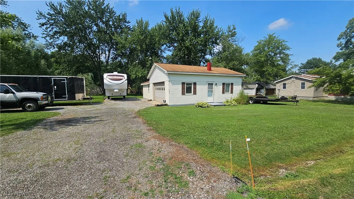 View of front of home featuring an outbuilding, a garage, a front lawn, and a chimney