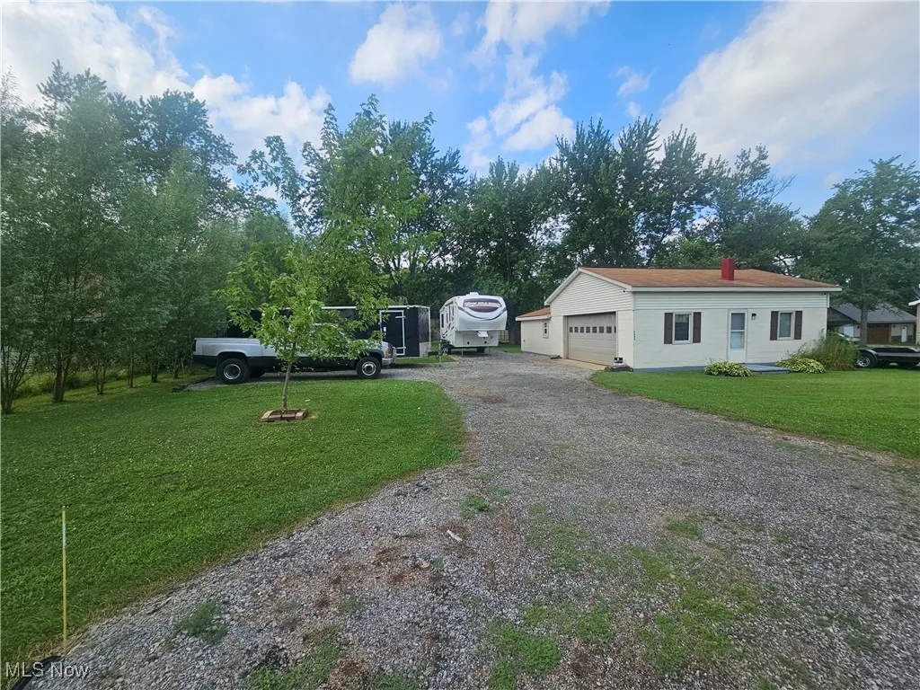 View of front of home with a garage, gravel driveway, and a front lawn
