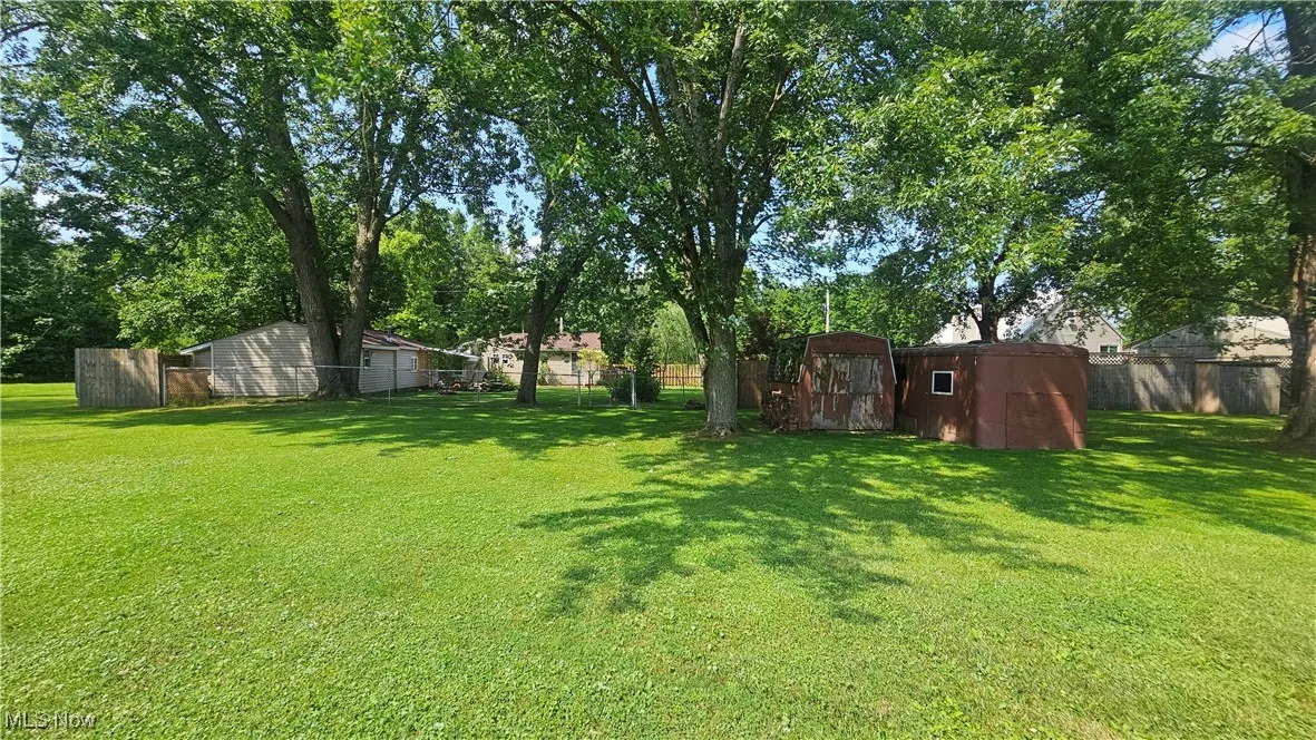 Fenced backyard featuring a storage unit