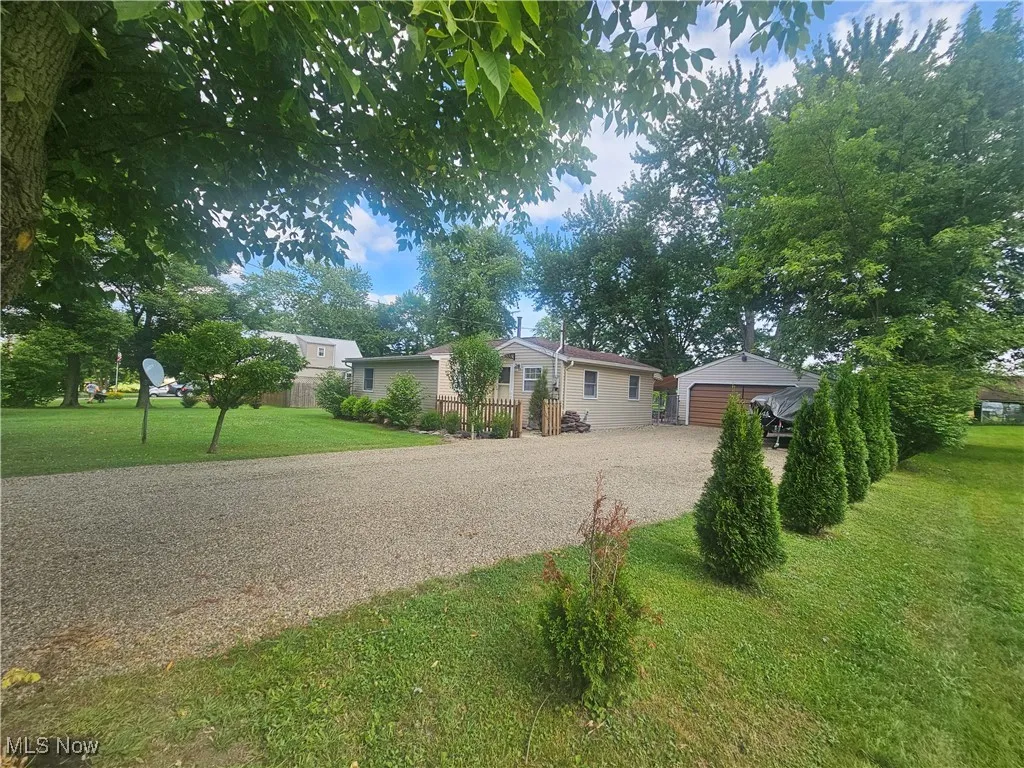 View of front facade featuring a front yard, an outdoor structure, and driveway