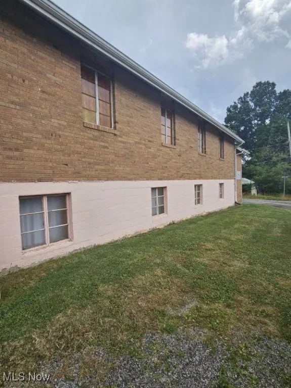 View of property exterior featuring a yard and brick siding