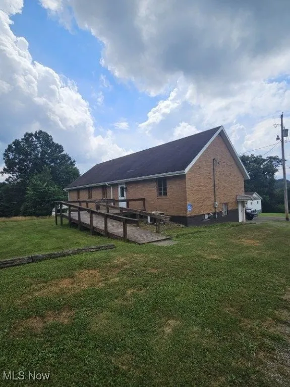 View of side of home with brick siding and a lawn