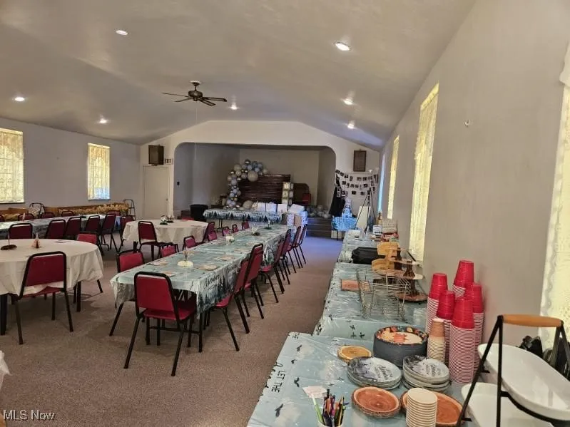 Dining room featuring lofted ceiling, carpet, and a ceiling fan