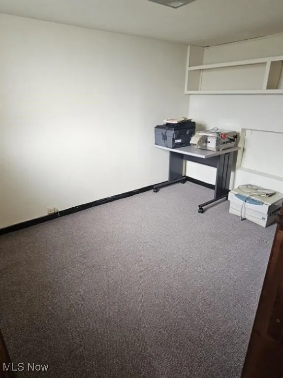 Carpeted office space with baseboards