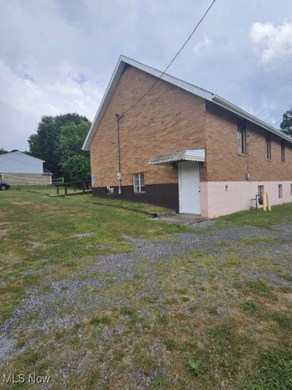 View of side of home with brick siding and a yard