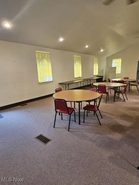 Carpeted dining area with recessed lighting and vaulted ceiling