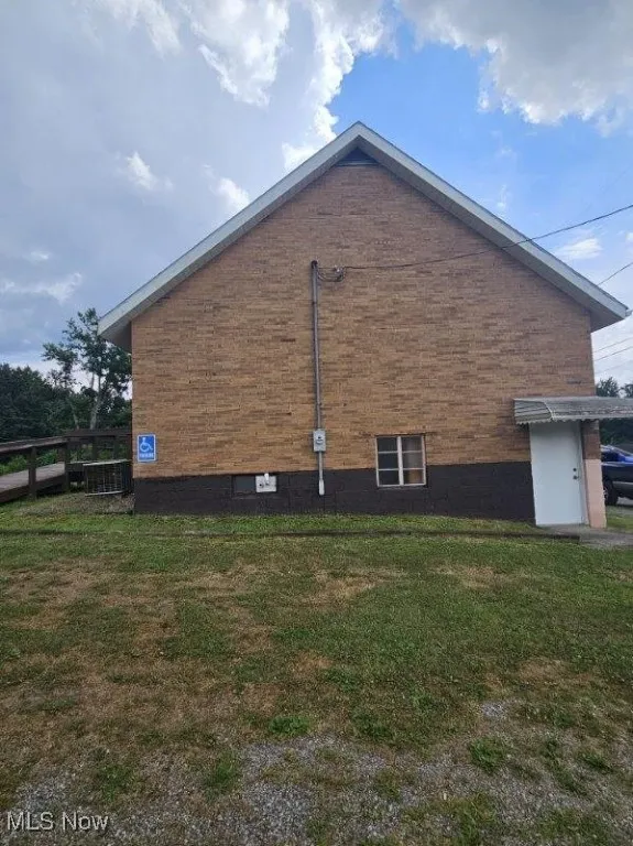 View of side of home featuring a lawn and brick siding