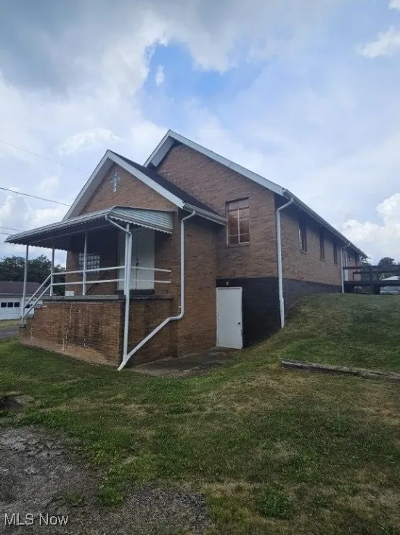 View of side of property featuring brick siding and a yard