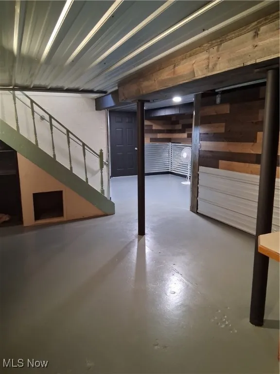 Finished basement featuring stairs and wood walls