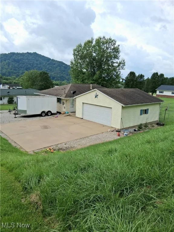 View of front of house featuring a mountain view, driveway, a garage, and a front yard