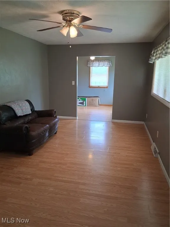 Living area featuring light wood-type flooring and a ceiling fan